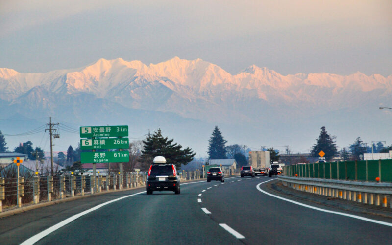 朝焼けの中、空いている高速道路を走る大人の車旅のイメージ